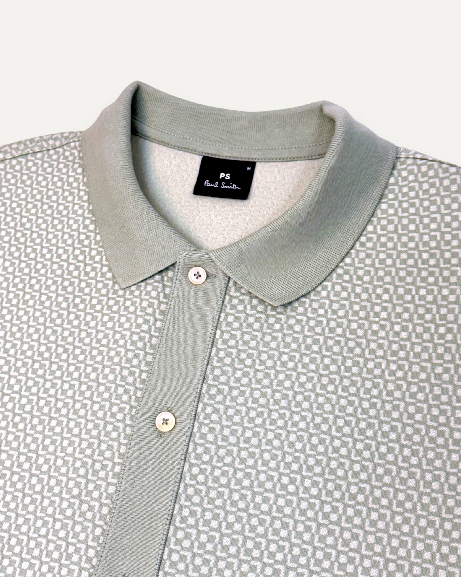 Close-up of a patterned shirt with a collar and brand label on a white background